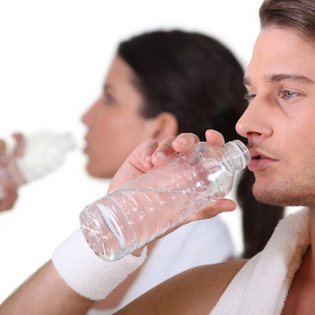 Couple in gym drinking water